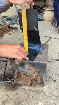 Metal worker using a square tool to align steel plates for welding in this industrial workshop motion footage