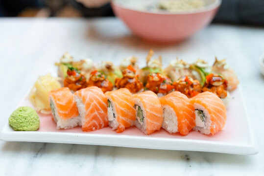 Elegant sushi platter on a white marble table in a fine dining restaurant. Fresh salmon nigiri and sashimi presented on a rectangular plate. Premium Japanese cuisine with appetizing gourmet style