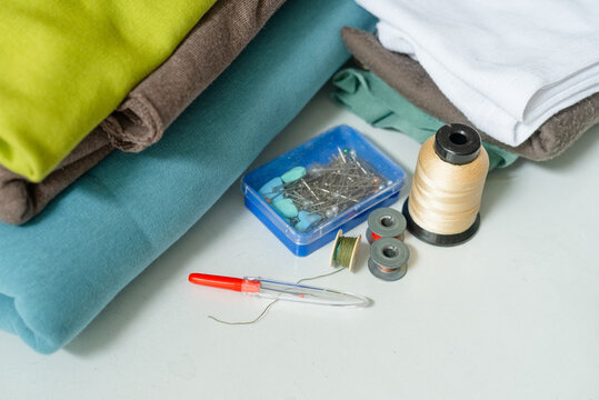 Fabric arranged with pins on white craft workspace for sewing. Sewing supplies for detailed organized textile preparation. Creative craft work with precise pinning and careful material handling