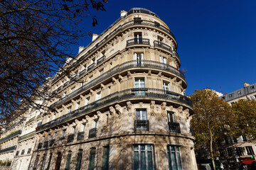 Majestic curved corner apartment building on Avenue de l'Observatoire in the 6th arrondissement of Paris, photographed under a deep cobalt blue sky in autumn.  © kovalenkovpetr