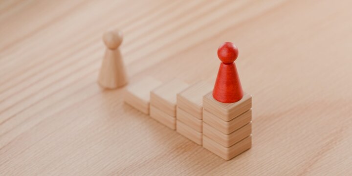 3d wooden pawn figurine looking up at another pawn placed high on building blocks. Building blocks of success, business and aspiration