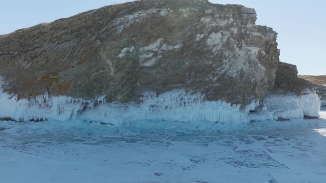 Aerial winter footage of rugged coastal cliffs and blue ice formations on Kharantsy Island, Lake Baikal, Irkutsk Oblast, Russia, with frozen water patterns