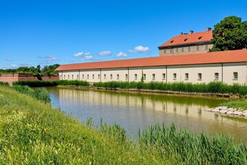 Fototapeta premium Historical Holic Castle chateau with defensive water moat and red tile roof under a clear blue sky in Slovakia.