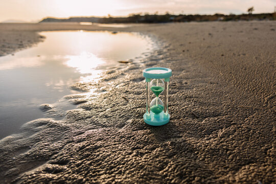 Hourglass on beach with sea and sand reflections