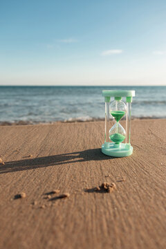 Hourglass on sandy beach with distant sea view