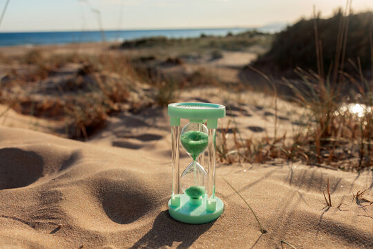Hourglass on sandy beach at sunrise