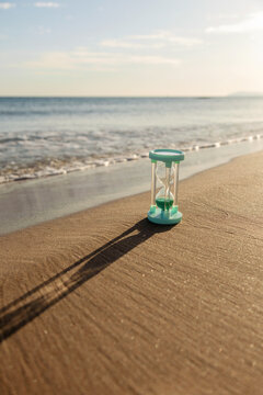 Hourglass casting shadow on sandy beach