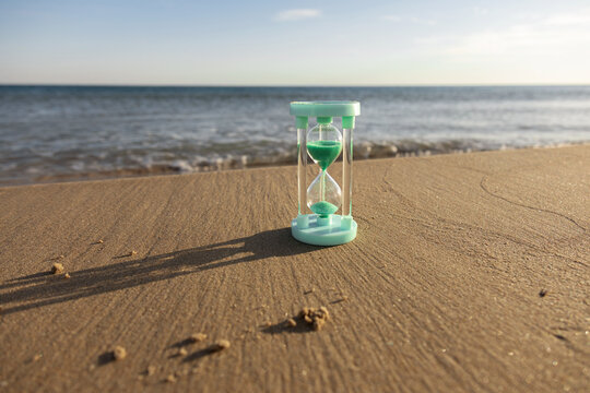 Hourglass on sandy beach with sea in background