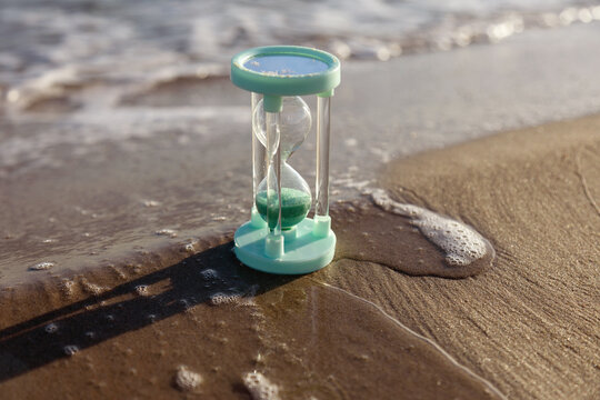 Hourglass by the seaside with sand and waves