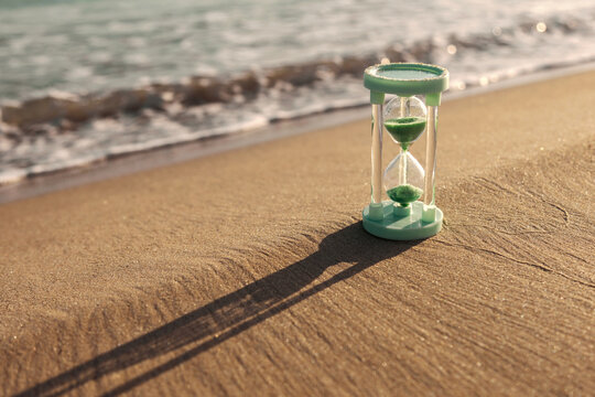 Hourglass casting shadow on sandy beach