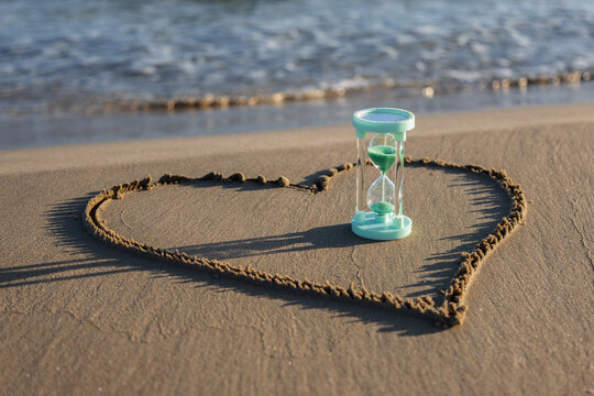 Hourglass on sandy beach with waves in background