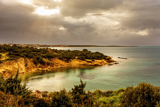 Coastal cliff landscape above calm sea under stormy sky