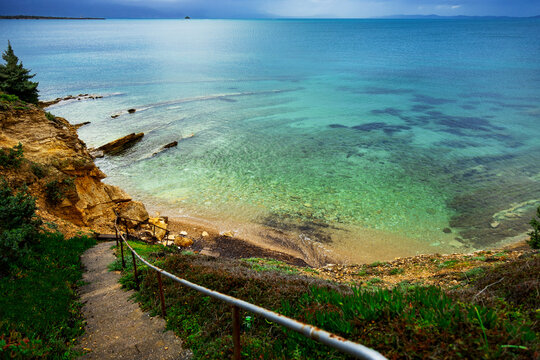 Turquoise sea by rocky shore with coastal path and cliff