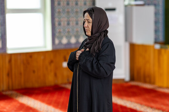Muslim woman praying quietly inside a mosque prayer hall