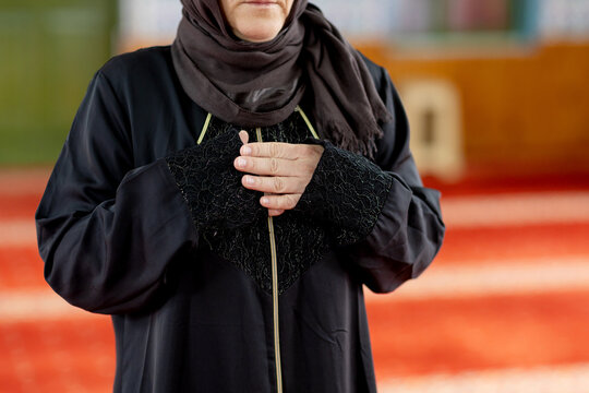 Muslim woman praying in mosque with hands clasped