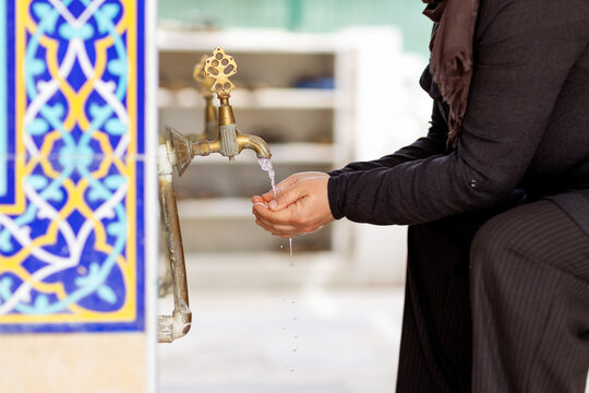 Muslim woman performing ablution at a mosque fountain