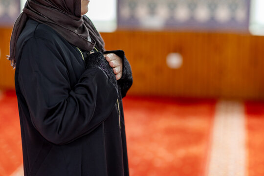 Muslim woman praying inside mosque with hands on chest