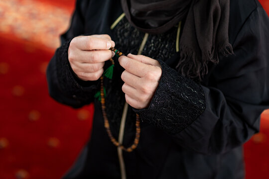 Muslim woman holding prayer beads inside a mosque