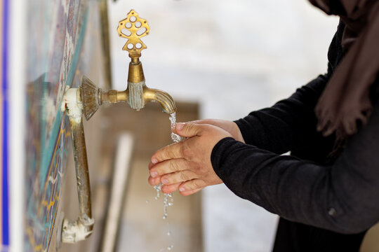 Muslim woman washing hands at mosque ablution tap