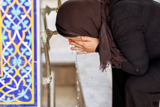 Muslim woman performing ablution at mosque fountain