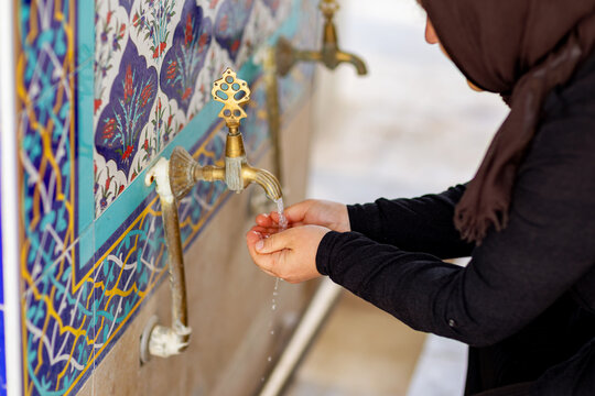 Muslim woman washing hands at mosque ablution fountain