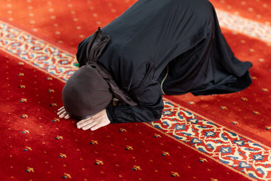 Muslim woman praying in mosque during salah on carpet