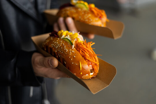 Street food hot dog with carrot slaw and mustard in hand