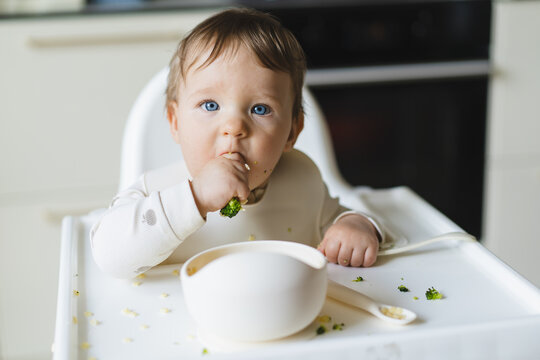 Baby enjoys eating complementary food in high chair