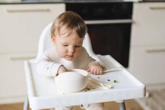 Baby enjoying complementary food in high chair