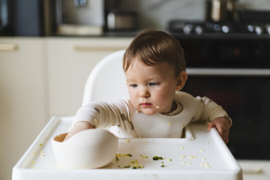 Baby in high chair eating complementary food