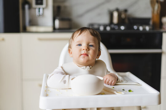 Baby eating complementary food in high chair