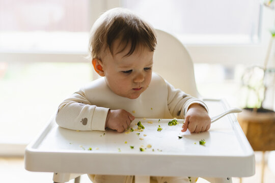 Baby eating complementary food in highchair