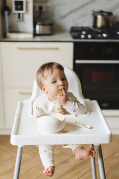 Baby eating complementary food in high chair