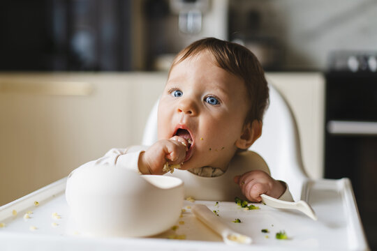 Baby eating complementary food in high chair