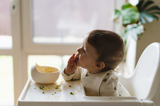Baby enjoying complementary food in high chair