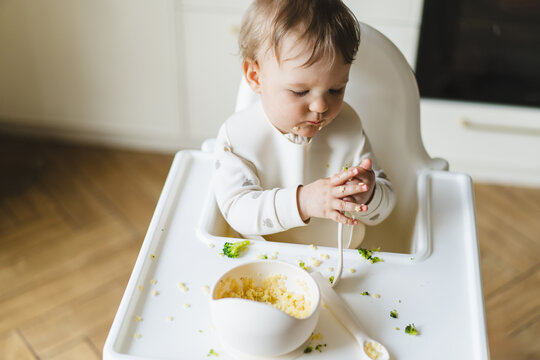 Baby exploring first foods in highchair with joy and mess