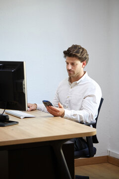 Professional working on computer and smartphone