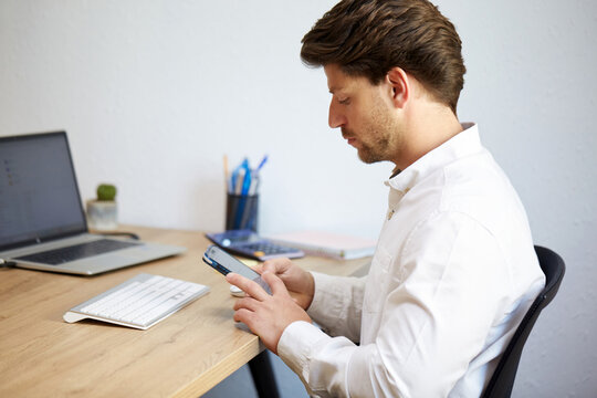 Professional man focused on smartphone at desk