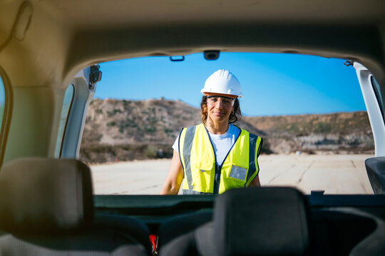 Woman construction worker in hard hat seen from car trunk