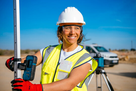 Female construction worker in helmet with survey equipment