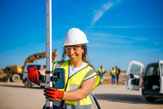 Female construction worker in helmet checking site level