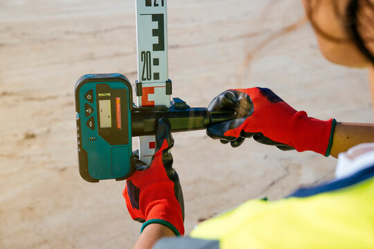 Woman construction worker using laser level for site safety