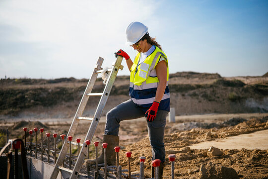 Female construction worker in helmet on site ladder safety