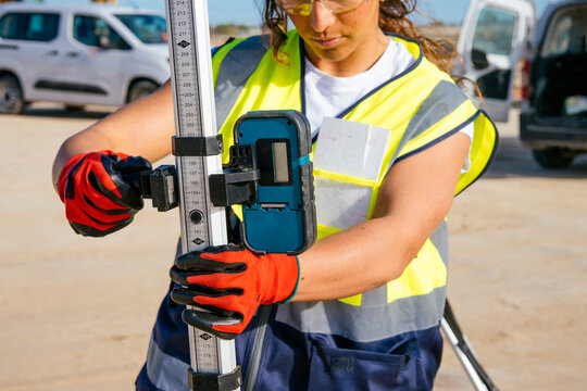 Female construction worker using survey equipment in safety gear