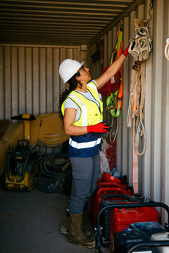 Female construction worker checking safety gear in container