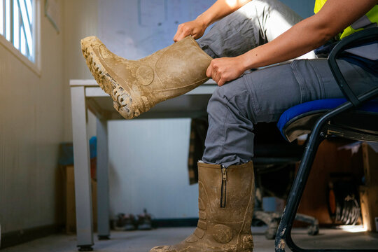 Construction worker putting on dusty safety boots indoors