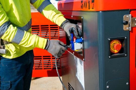 Worker connecting industrial power cable to generator unit