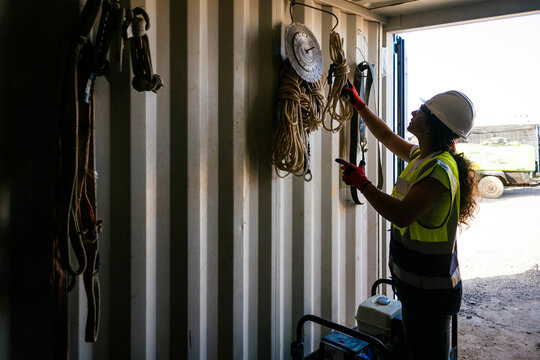Female construction worker organizing safety gear in container