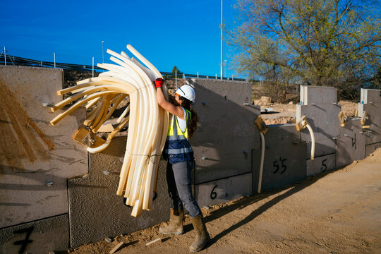 Woman construction worker lifting bundled foam insulation