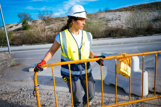 Female construction worker moving safety barrier at road site